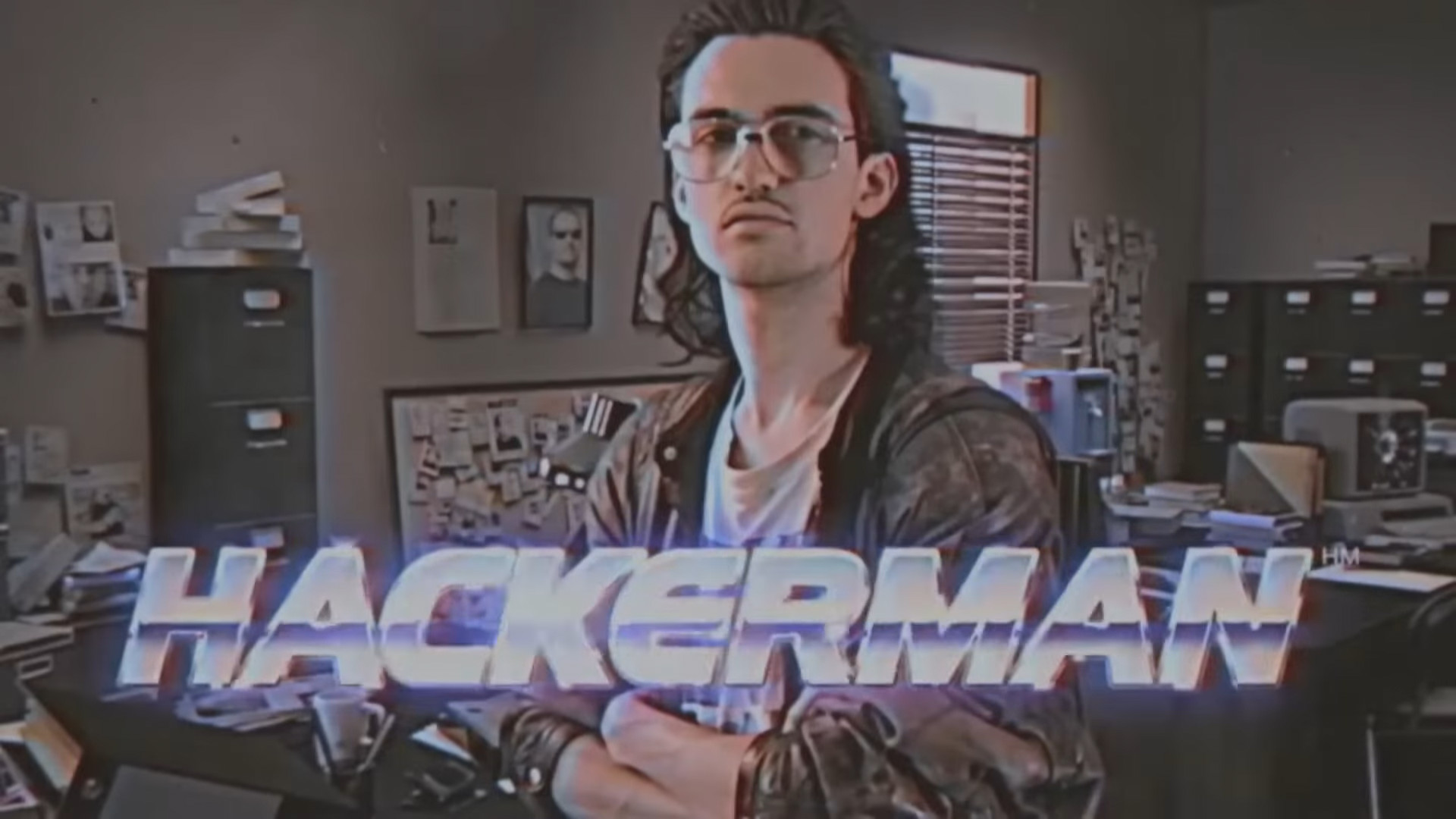 Capture d'un avec un homme aux cheveux longs (coupe mulet), lunettes des années 70, et le texte 'Hackerman' écrit en police futuriste en titre